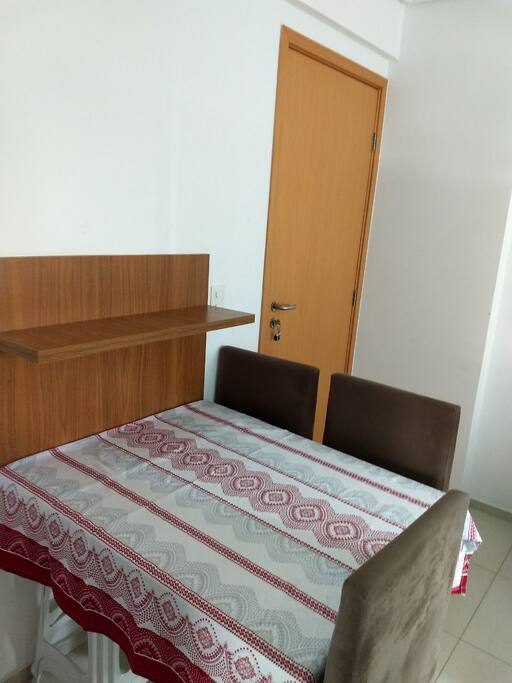 Mesa de jantar com para quatro pessoas, com 3 cadeiras e um banco.
