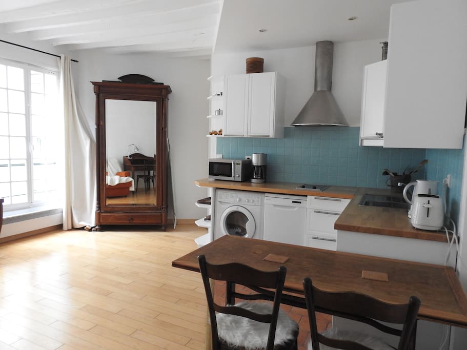The living room has 2 windows facing the courtyard and it is furnished with a dining table, a queen convertible sofa bed, a desk, cable TV, wardrobe, hard wooden floor.