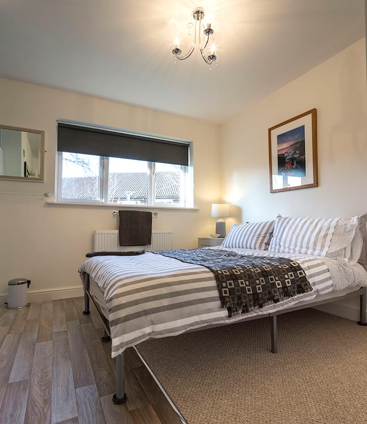 2号卧室（ 1楼）双人房可俯瞰前花园。 设有立式衣柜、床头储物柜、大淋浴间和盥洗盆。 隔壁有共用厕所和洗手盆。