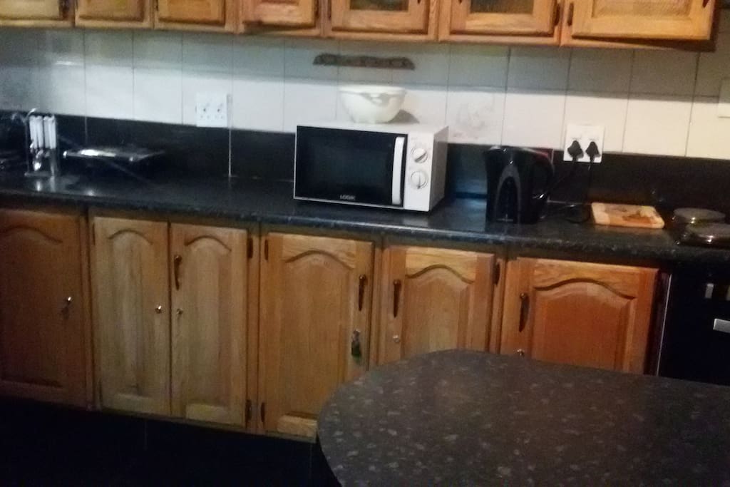 Large kitchen with stove and oven, washing machine, fridge and cupboards for storage.