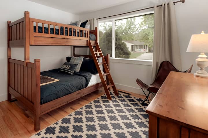 Camas individuales sobre las literas Full Pottery Barn con colchones de mechones y agujas. Vestidor para guardar. Los juguetes para niños y los libros están en cestas.