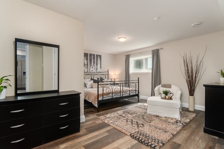 غرفة نوم رئيسية كاملة بسرير كينج مريح وخزانة ملابس وستائر معتِّمة. اجلس على كرسي مريح وعثماني أمام مدفأة كهربائية 