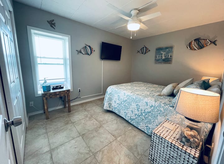 First bedroom with queen size bed with ample plugs next to the bed. Enjoy a window looking out towards the dunes. Keep it open at night to hear the waves. 