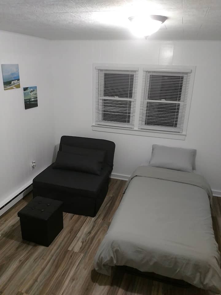 غرفة نوم ثانية وسرير واحد مرتب.  يحتوي التوأم على أغطية سرير إضافية. 