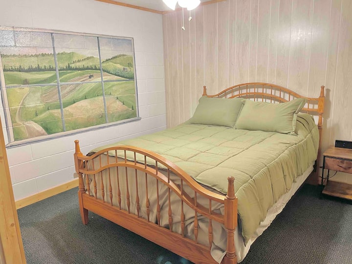 غرفة النوم الأولى من مدخل الطابق السفلي إلى اليمين. سرير بحجم كوين ومنضدة جانبية وخزانة في هذه الغرفة إلى جانب أخلاقي جميل للإطلالة من الكوخ. 