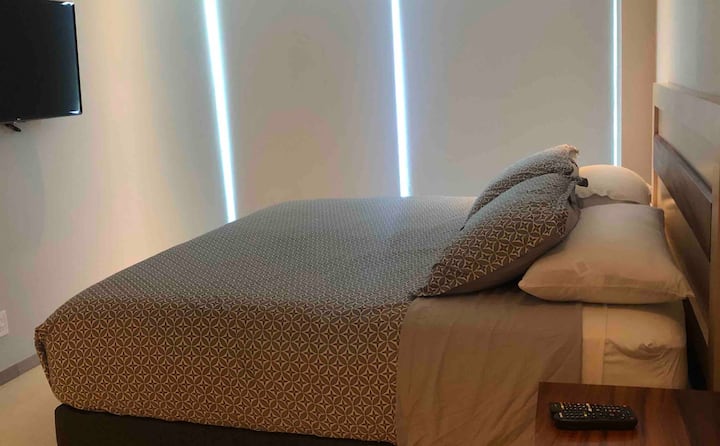 Een slaapkamer met een kingsize bed, een tv en een eigen badkamer, met een balkon.