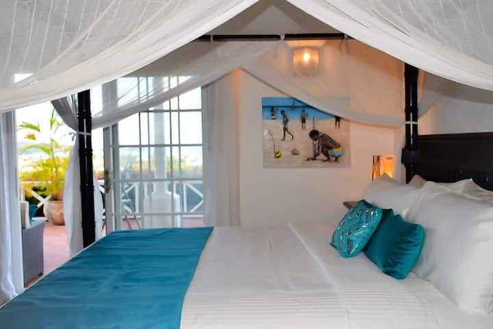 Master Bedroom with full en-suite bathroom. King canopy bed with  netting. AC and ceiling fan in every room. Leads to private sitting area outside overlooking the sea. 