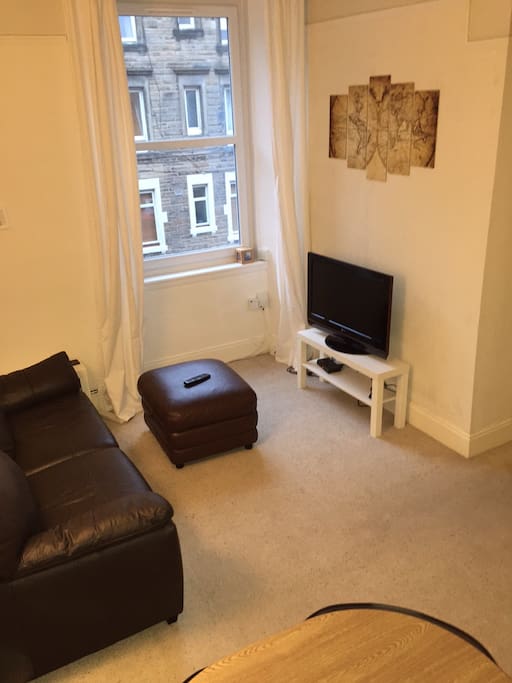 The living room features a widescreen tv and comfortable couch along with a table for eating