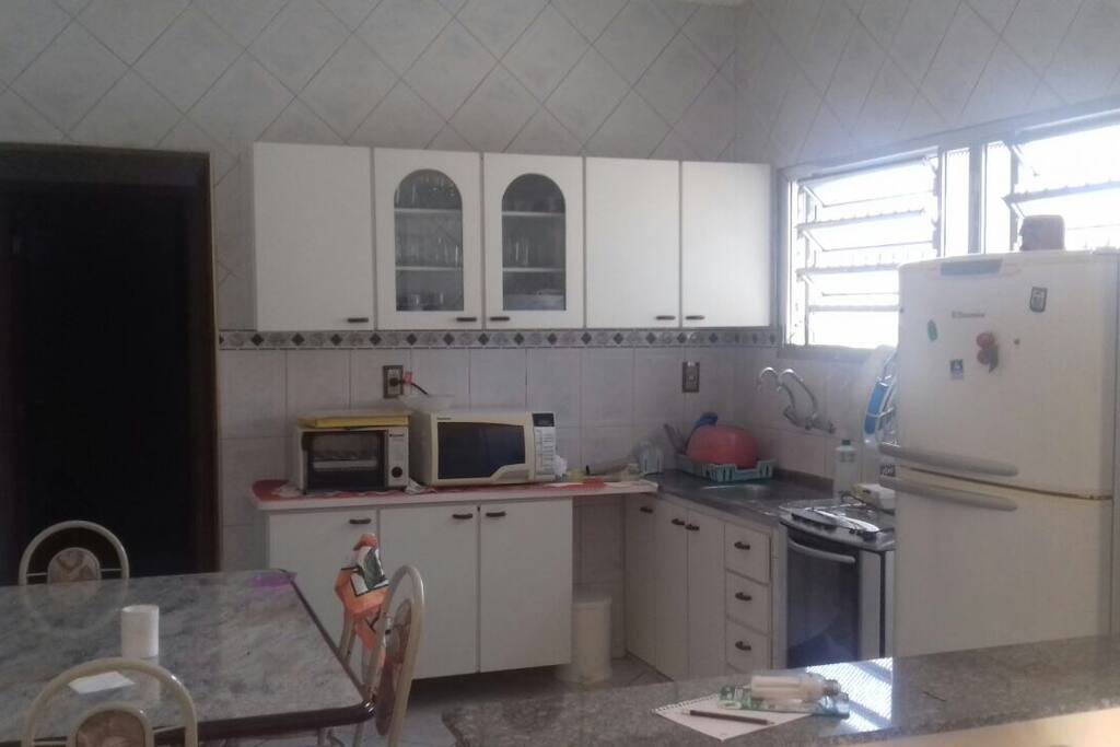 Cozinha americana, com fogão, geladeira, forno eletrico e microondas, louças, panela e todos os utensilios necessários para preparar suas refeições.