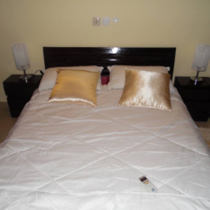Chambre disposant d'un lit de deux places avec deux lampes de chevets et une grande penderie