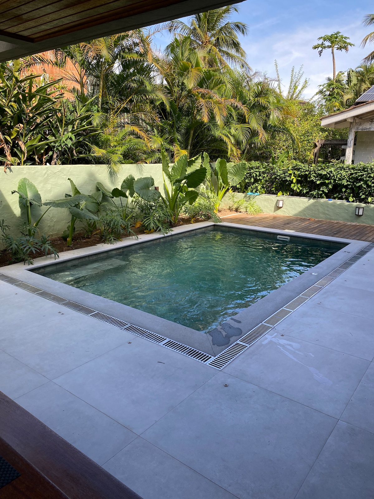 A private pool is surrounded by tropical greenery, creating a serene environment. The pool features a modern design with a stone border and subtle lighting, while lush plants provide a natural backdrop, enhancing the sense of tranquility.