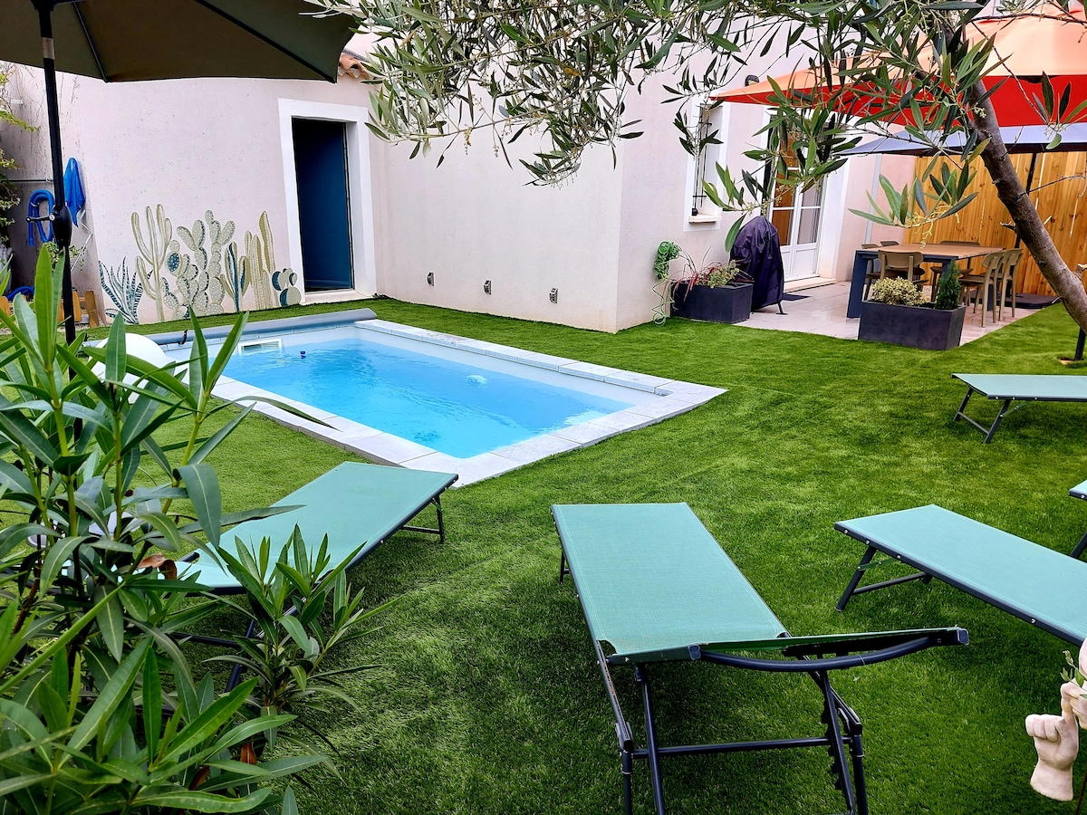 A private garden area features a small swimming pool surrounded by manicured grass. Lounge chairs are placed for relaxation, and potted plants add greenery. An outdoor dining space is visible in the background, providing an opportunity for al fresco meals.