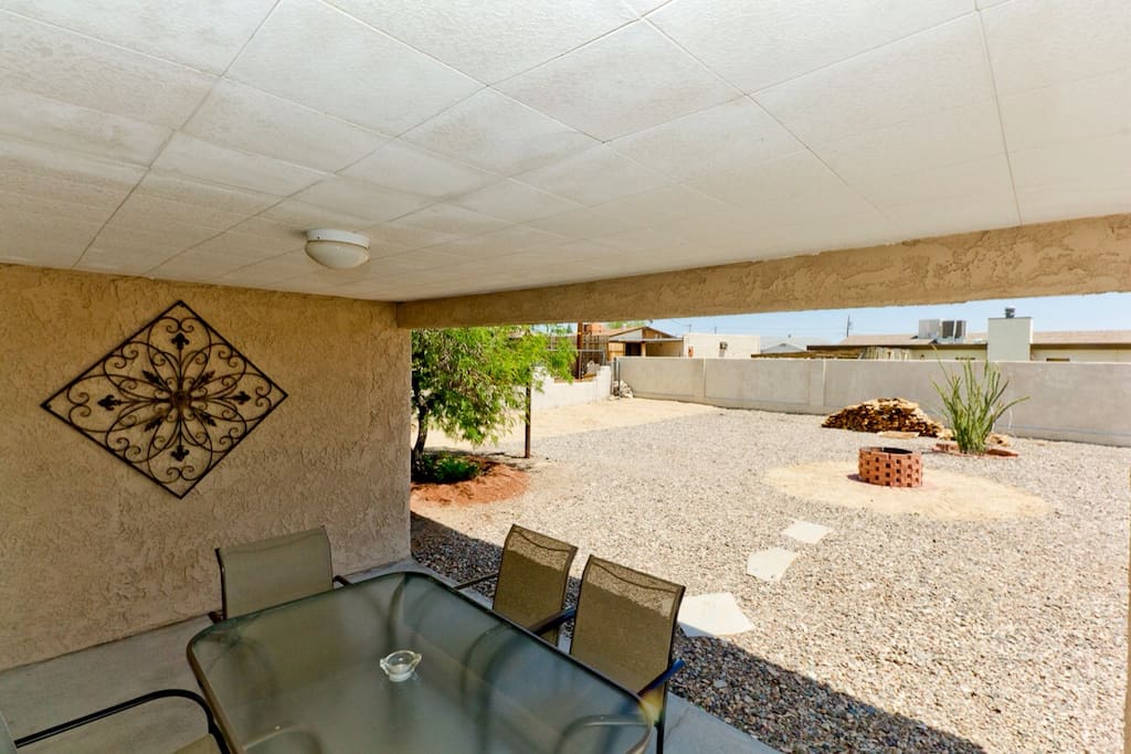 Large backyard with fire pit and a newly built addition to the porch which spans the whole length of the house with fans and a bbq