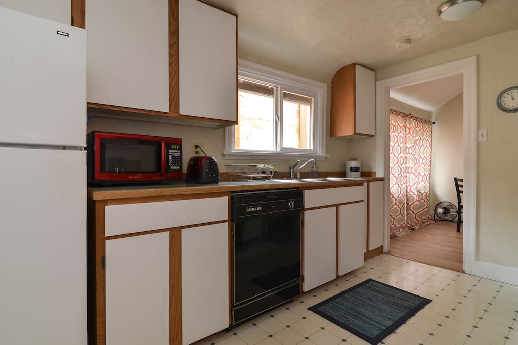 Spacious kitchen with a full sized gas range, dishwasher, warm lighting, modern comforts and quality dishes and cooking tools.