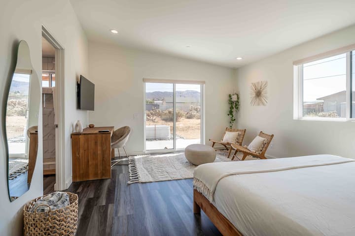 Primary bedroom with king sized bed, wall mounted TV on swivel arm and black out blinds