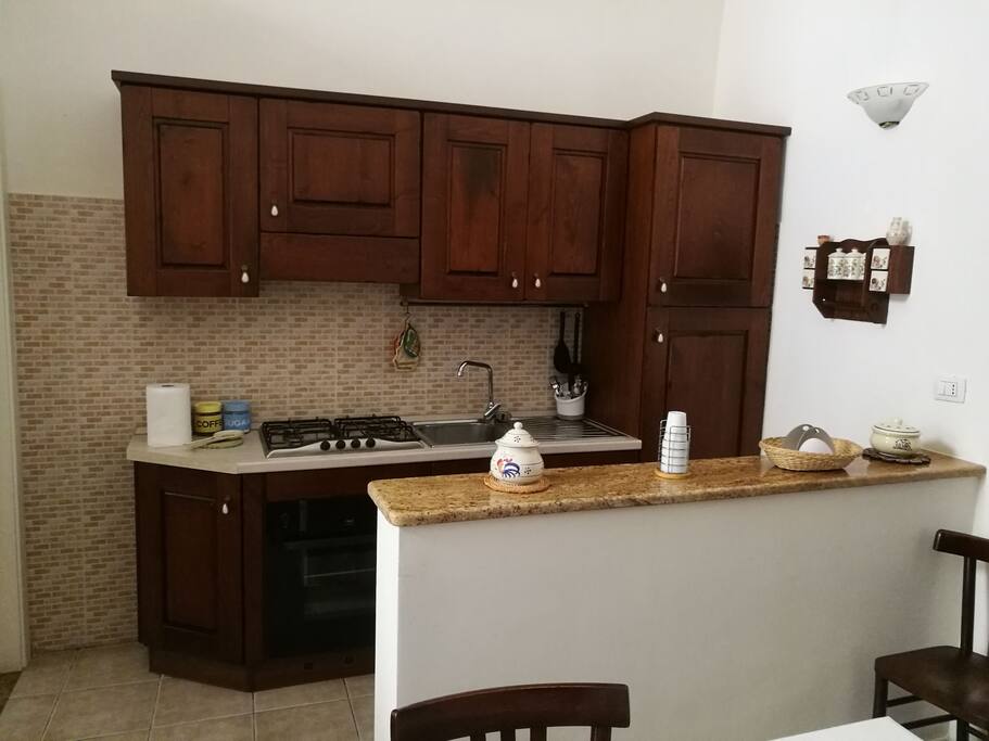 Angolo cottura con frigo, forno e fornelli.