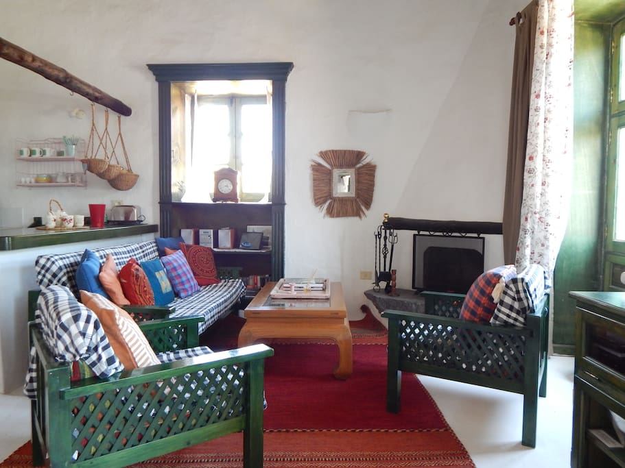 Spacious lounge with high ceilings, fireplace and large windows with views of surrounding hills, pool and garden area