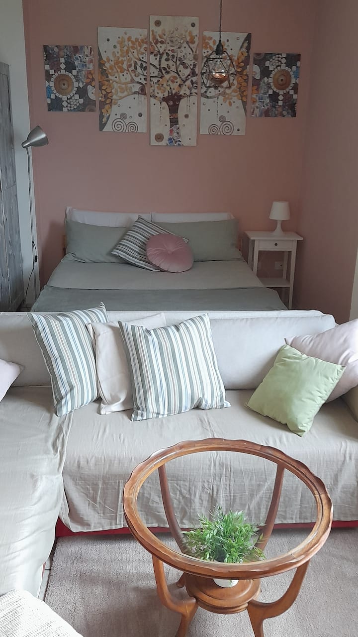 Kitanda cha ukubwa wa watu wawili nyuma ya sofa, sehemu iliyo wazi.