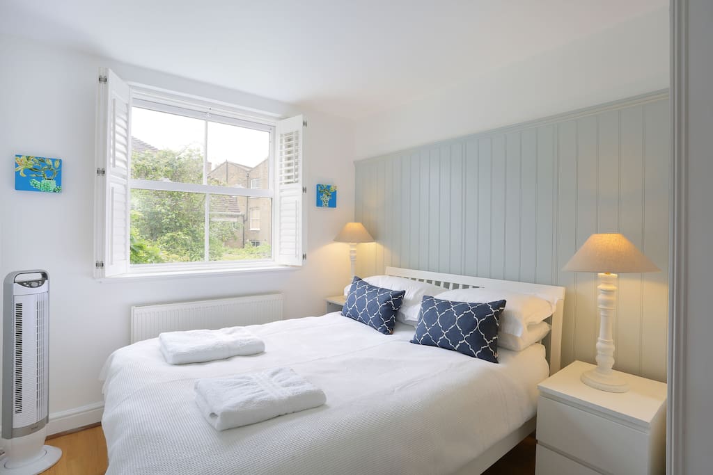 Upstairs bedroom; Uk size double bed. Plug in aircon unit. White shutters.