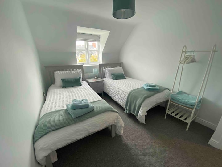 Zweibettzimmer mit Hängebereich und Kommode für Kleidung.