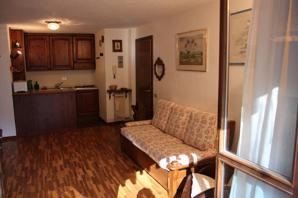 sala con divano letto matrimoniale e angolo cottura sul fondo