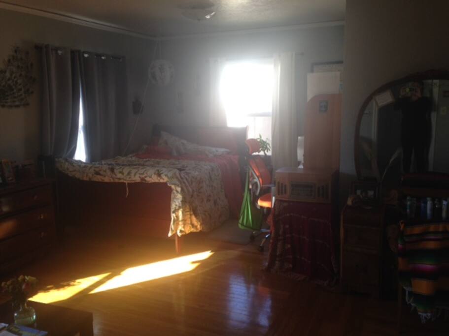 sleeping and working area in giant, sunny room (bed, desk with hutch)