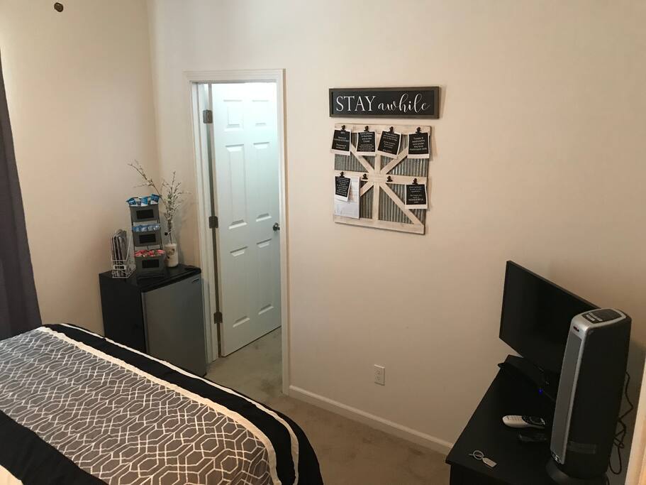 Guest bedroom has an attached walk-in closet, ceiling fan, space heater, mini fridge, and TV with DirectTV