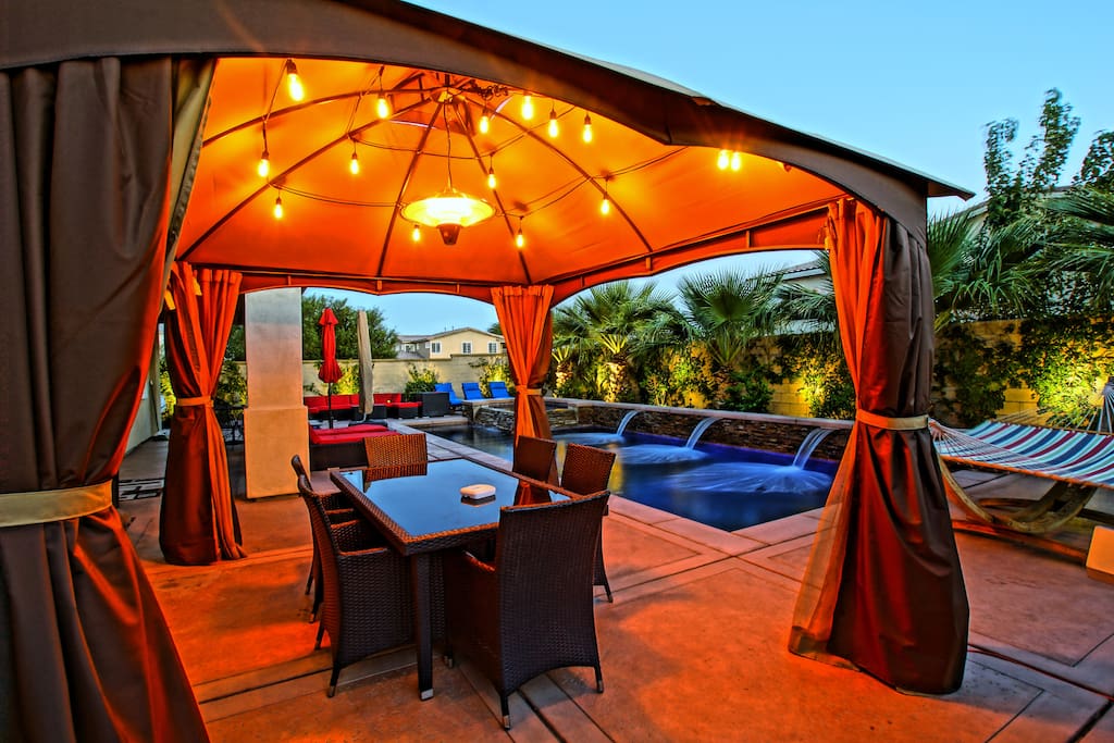 Resort Style Living - Covered outdoor Dining with string lights and hanging latern heater