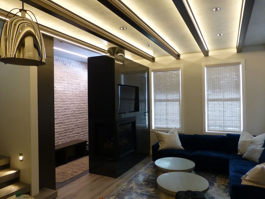 Main living area, velvet sectional, steel cladded gas fireplace, television, Sonos music system.