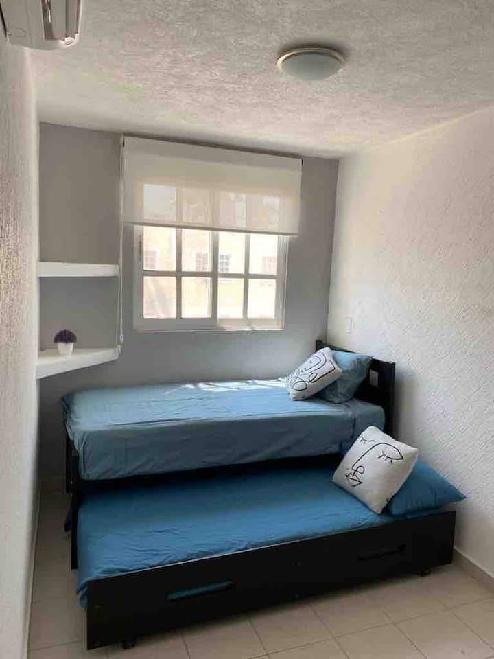 Chumba cha kulala chenye vitanda viwili, kabati na kiyoyozi cha mtu binafsi ambapo unaweza kupoa na kupumzika.