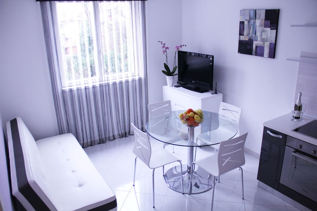 Living room with sofa, TV, kitchen and table for four