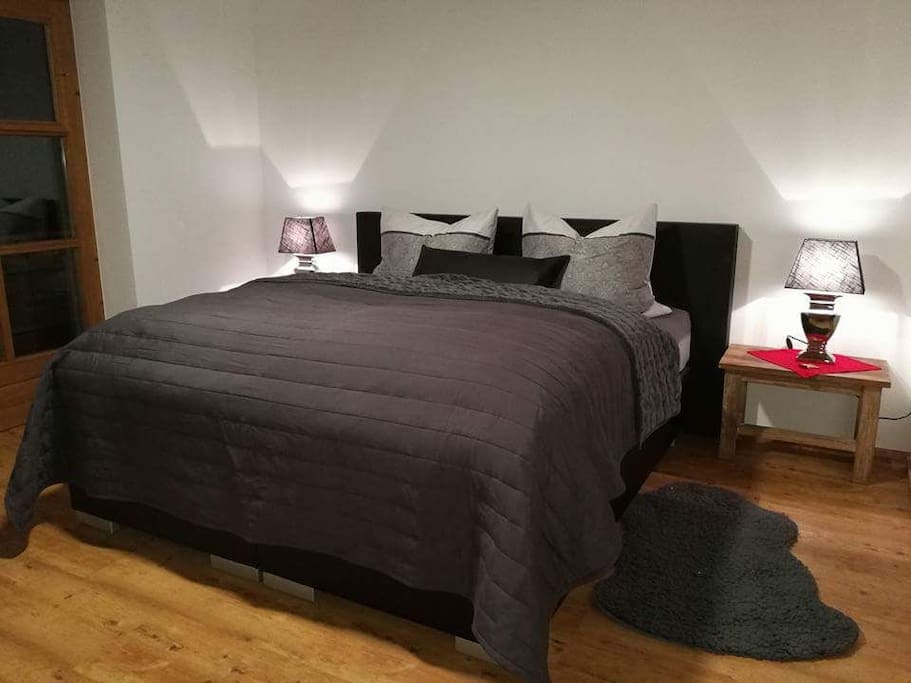 Schlafzimmer mit großem Doppelbett und Zugang zum Balkon