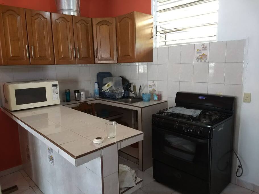 cocina con estufa, microondas, alacena con utensilios suficientes