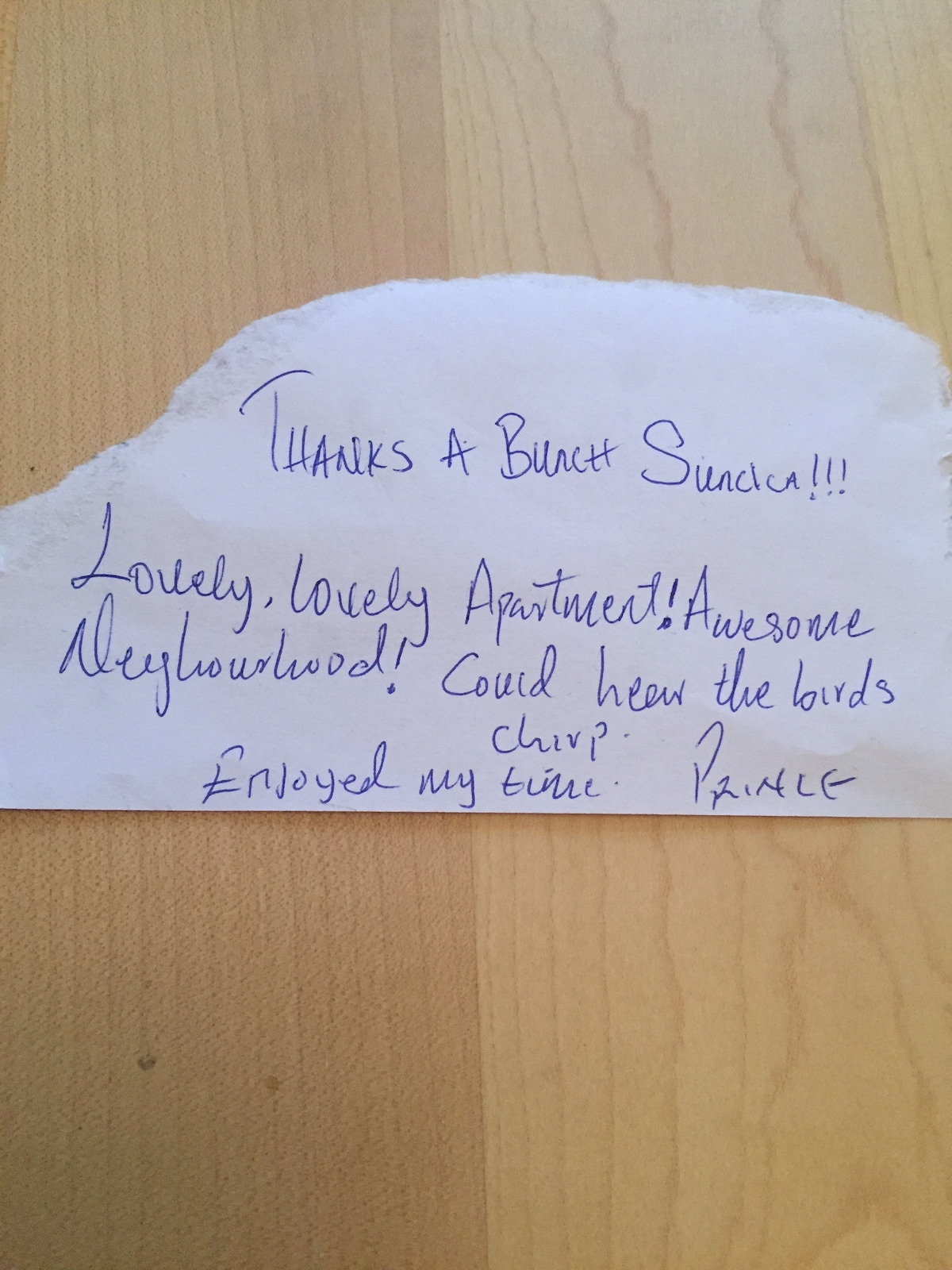 A handwritten note on a piece of paper is visible, expressing gratitude and positive sentiments about the apartment and the neighborhood. The paper is slightly torn at the top, and the writing features a mix of blue and black ink, with informal phrasing noted throughout.