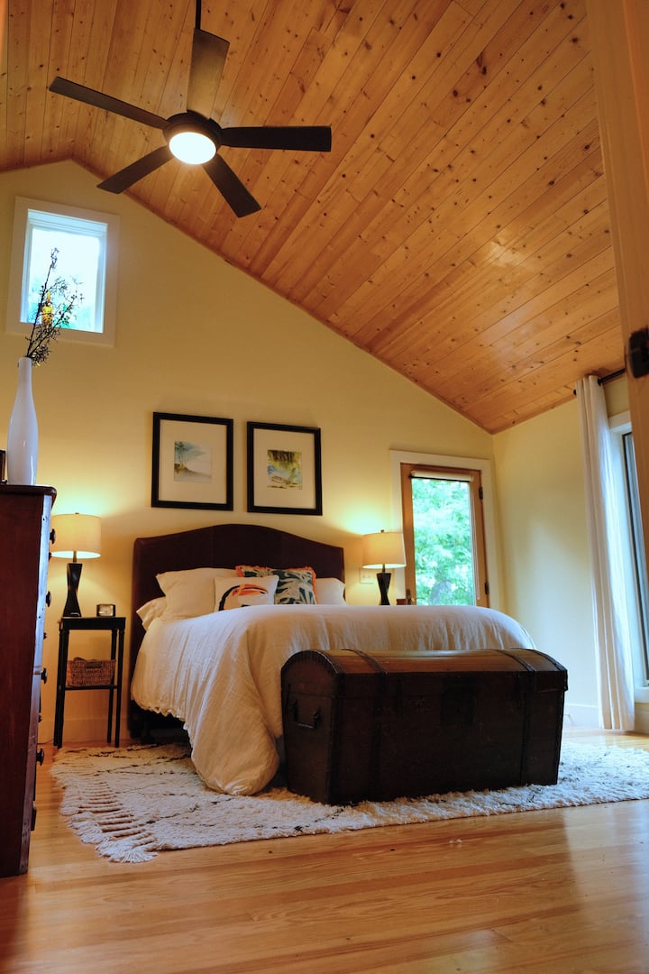 Dormitorio principal con techos lofts de doble altura, baño privado con bañera de hidromasaje y acceso privado al porche.