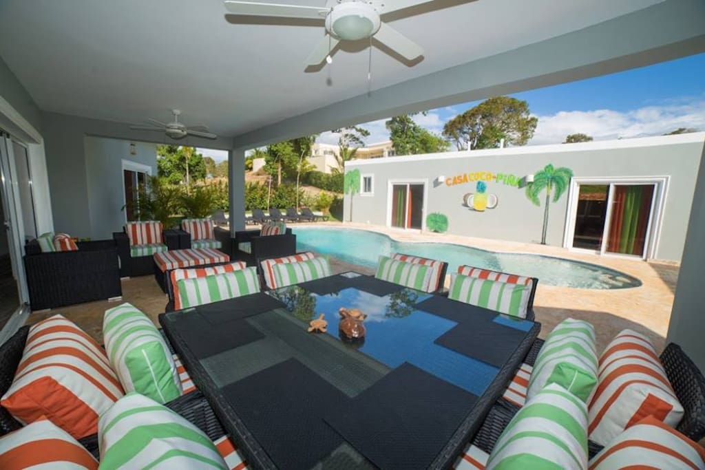 CASA COCO-PINA covered terrace houses an over sized custom dining table & 8 chairs as well as custom entertainment seating