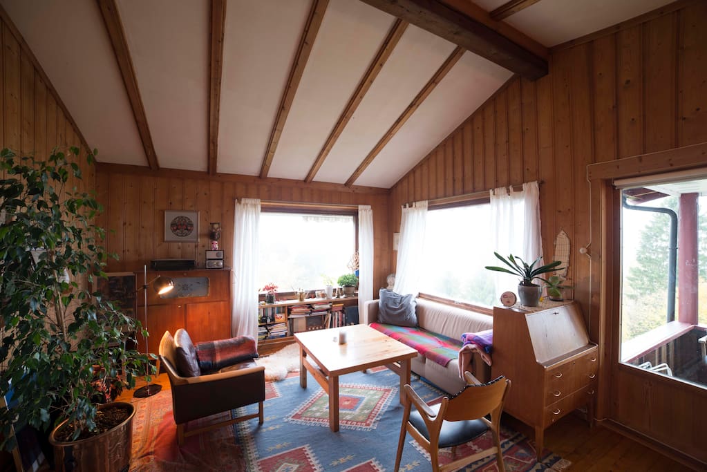 The living room has a high ceiling and a 180 degree view of the fjord through the windows.
