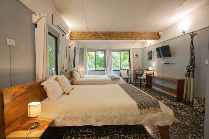 Autre angle de la chambre à l'étage avec deux lits queen size, entourée de verdure tropicale