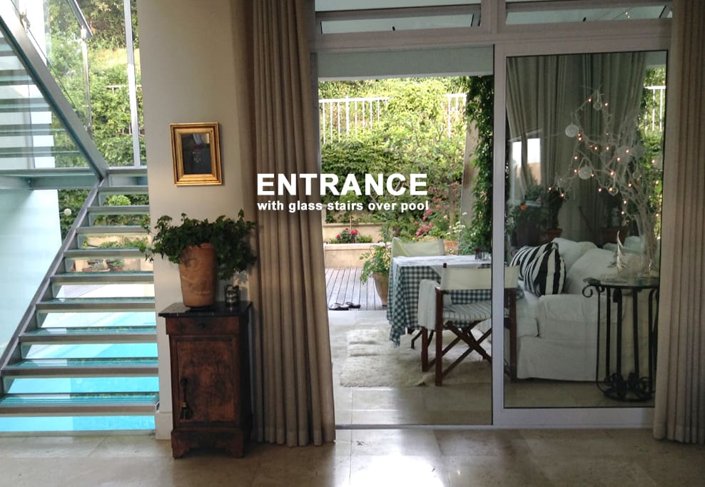 The entrance hall faces an unusual glass and steel staircase providing natural light throughout the central space overlooking the pool and the garden