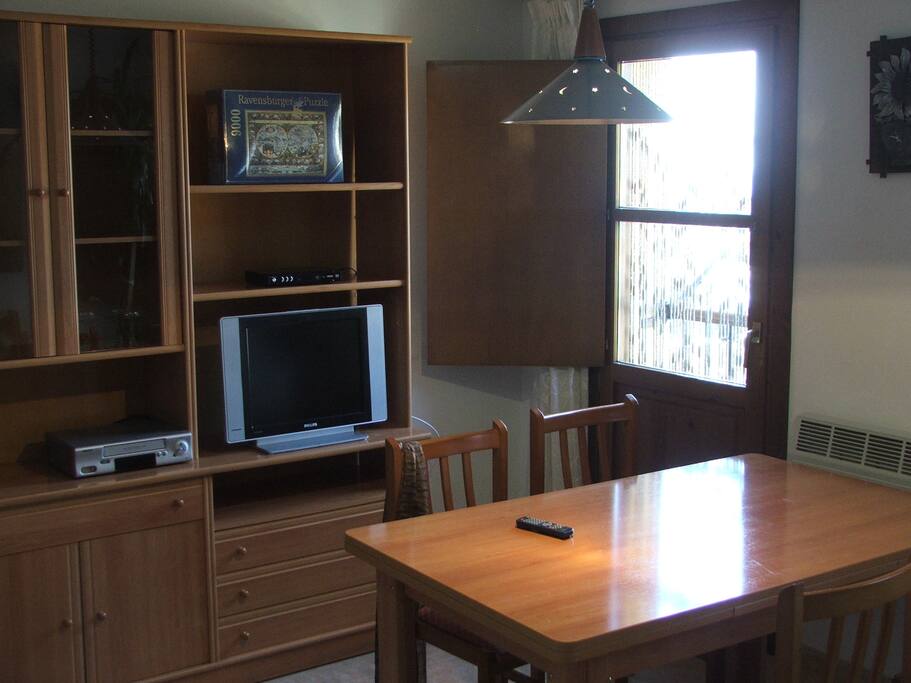 Salón con TV mesa de comedor plegable, sofá y gran estantería para dejar todas tus cosas