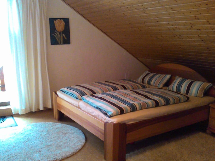 Schlafzimmer mit Doppelbett und Balkonzugang.