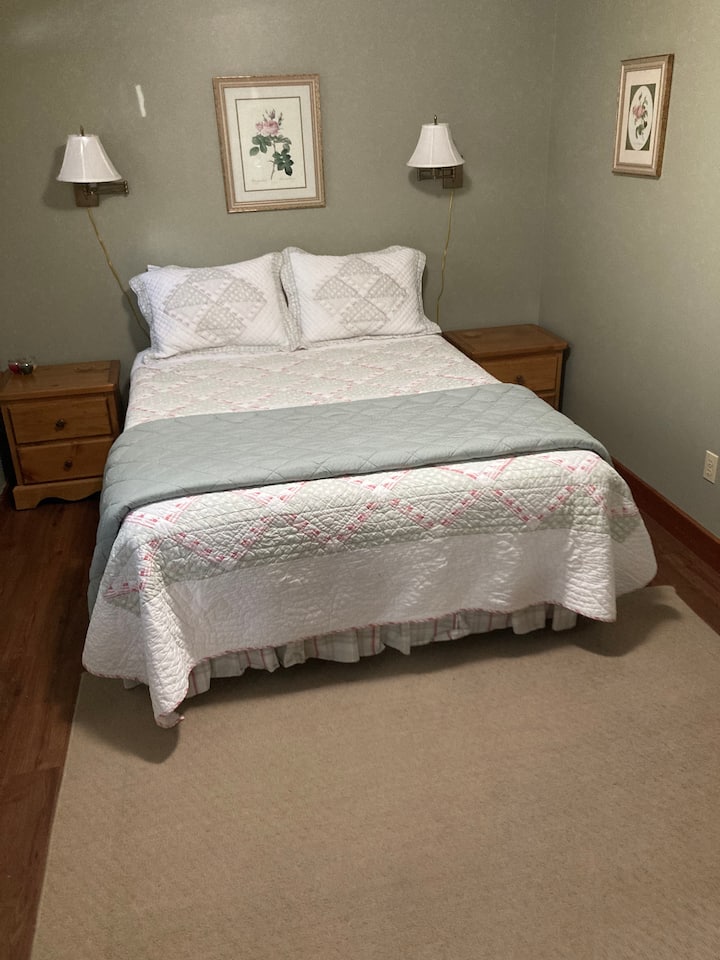 Საძინებელი #1 საწოლით, საწოლთან და მდივანთან. 8.5’ x10’ ოთახი მისაღებიდან/სასადილოდან ორი ნაბიჯით დაბლა მდებარეობს. Ტყუპი საძინებელზე წვდომა მოიპოვება ამ ოთახის მეშვეობით.