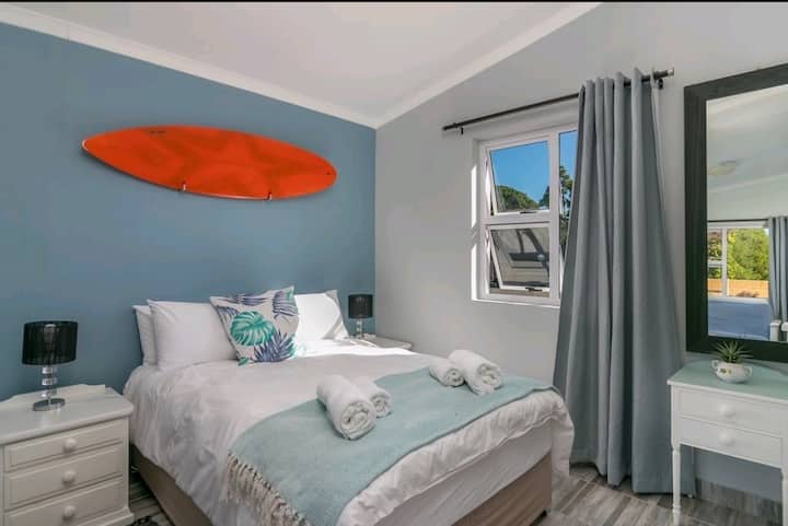 This charming bedroom in the self-contained flatlet features a cozy double bed and beach-inspired decor.  Natural light fills the room, offering a peaceful retreat with easy access to the en-suite bathroom and kitchenette.