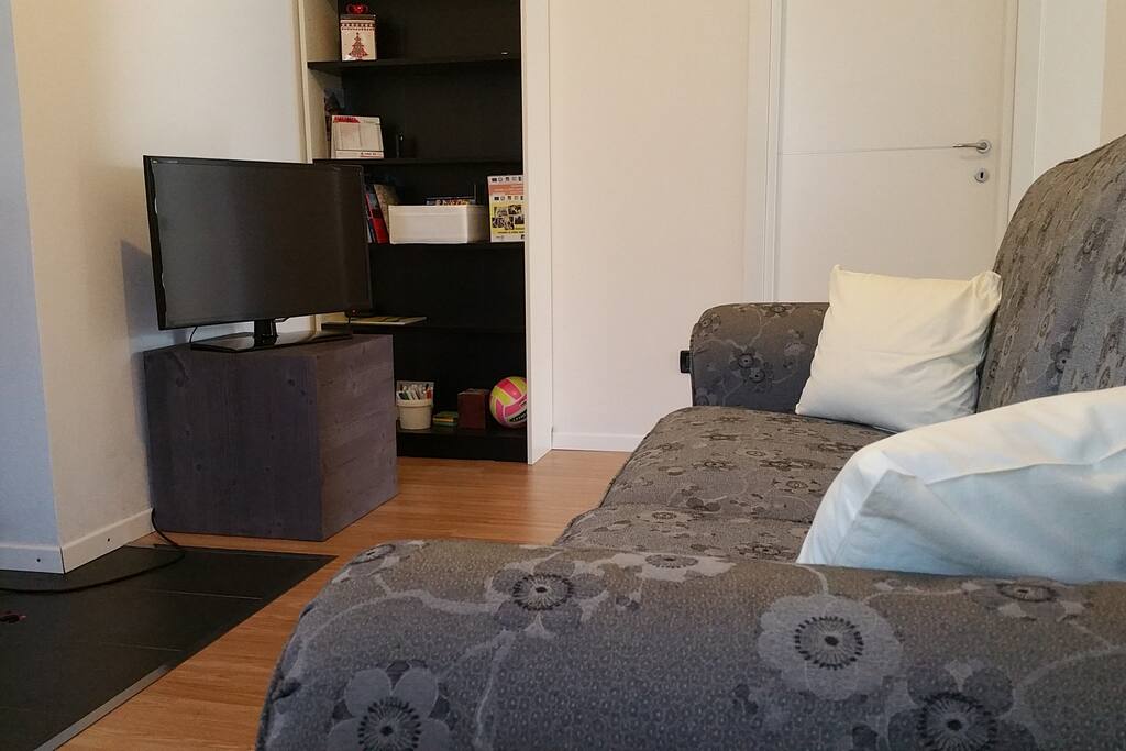 Salottino con divano tre posti e televisione.