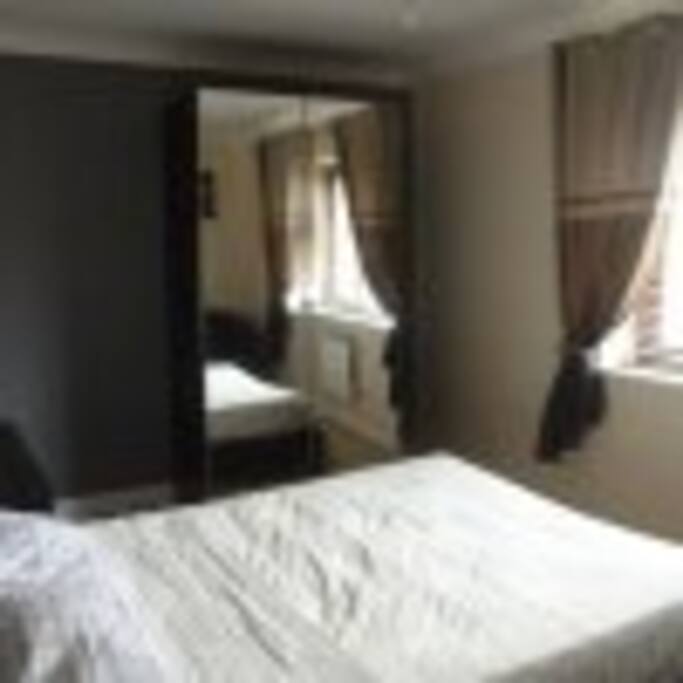 Spacious double bedroom with double wardrobe and ample drawer space and small double tub sofa.