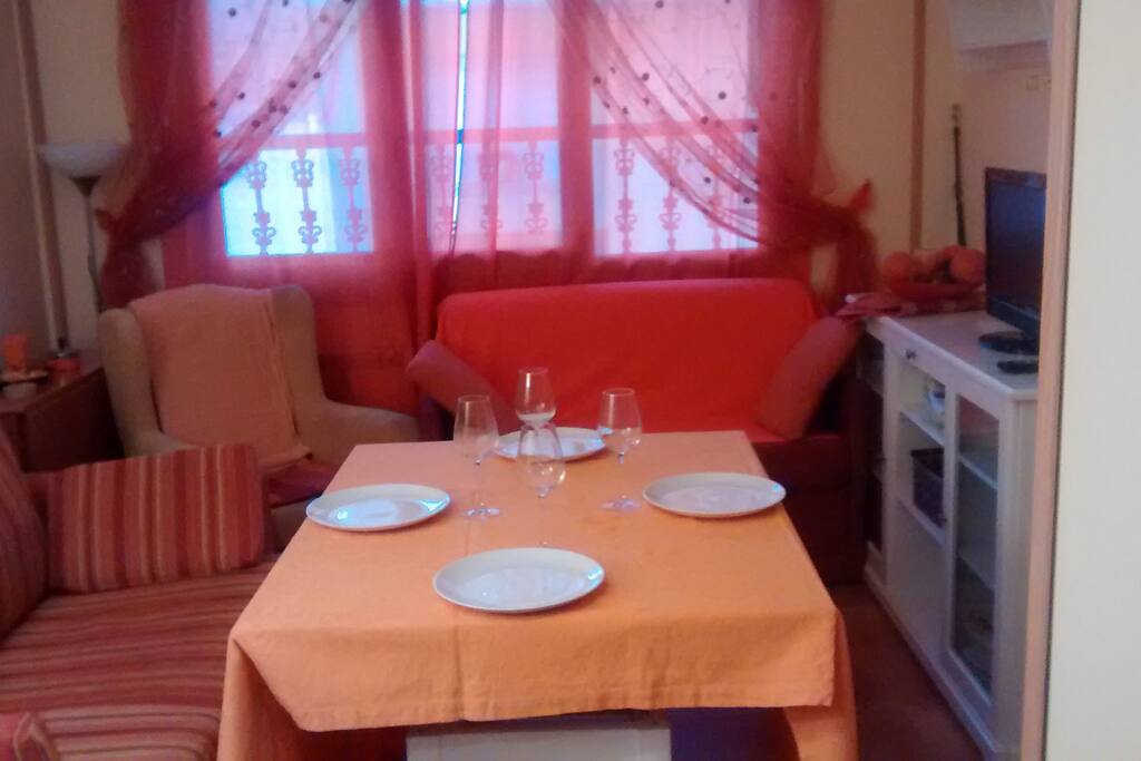 Salón comedor con mesa, sillas, sofá-cama, butaca, TV.
