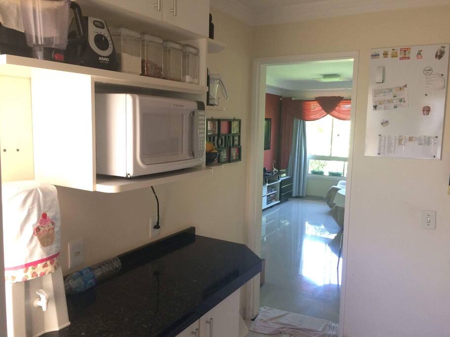 Cozinha completa com armários e utensílios; conta com geladeira, forno, fogão, microondas, liquidificador, torradeira, sanduicheira, batedeira, espremedor de frutas e cafeteira.