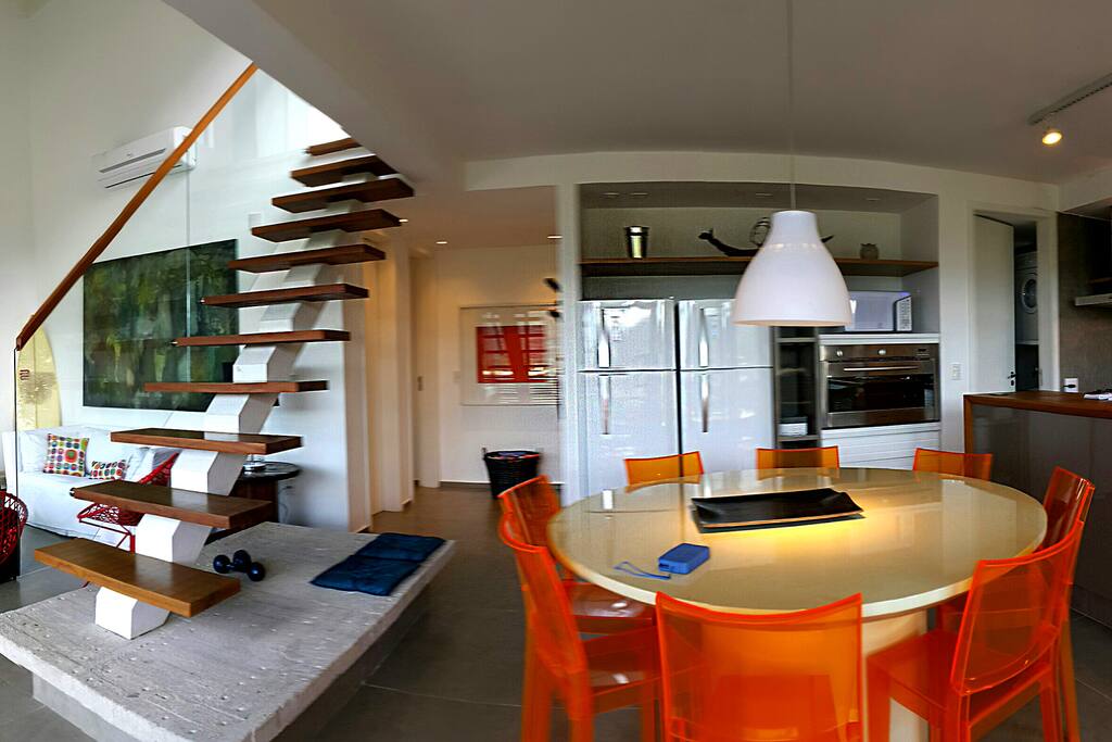 Living amplo integrando jantar com cozinha Gourmet americana.