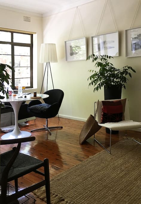 Sun filled dining/lounge room with designer furnishings looking onto treelined street