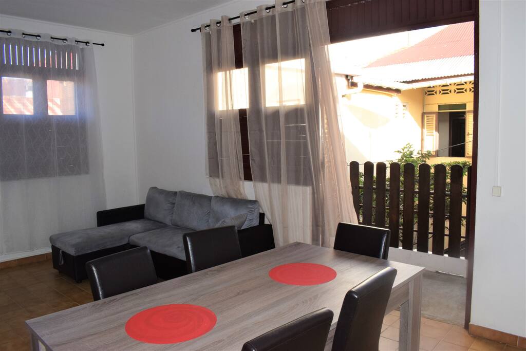 Séjour lumineux et équipé d'une tv, ventilateur mural, table à manger et canapé d'angle convertible